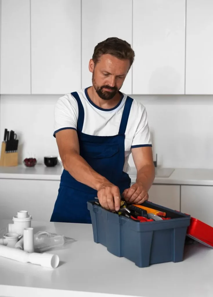 A professional plumber in Jersey selecting tools from a toolbox for a plumbing job.