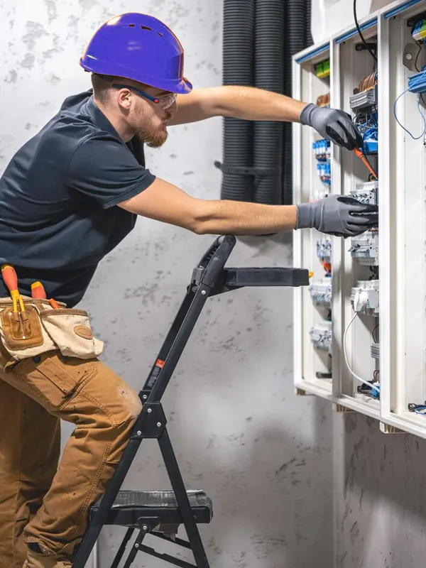 A Jersey electrician working on an electrical panel, carefully inspecting and adjusting wiring.
