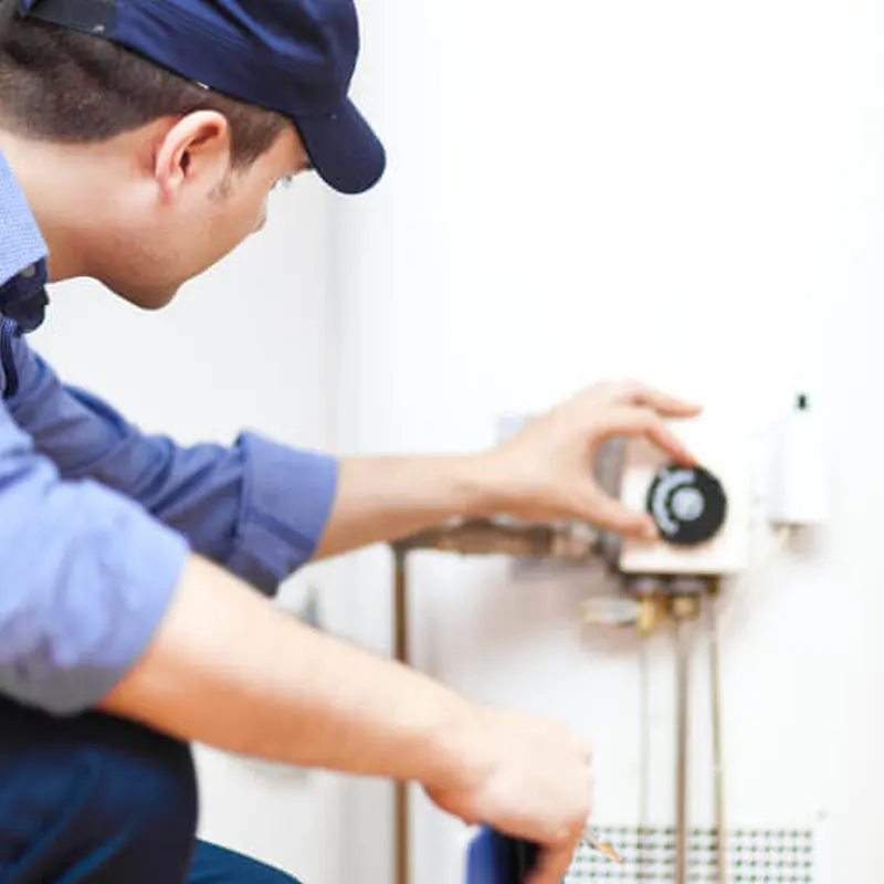 A heating engineer adjusting a water heater thermostat for emergency heating repairs in Jersey.
