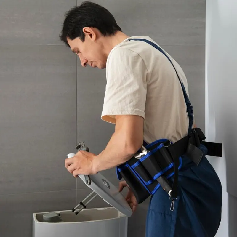 A local plumber in Jersey inspecting a toilet tank for leaks and repairs.