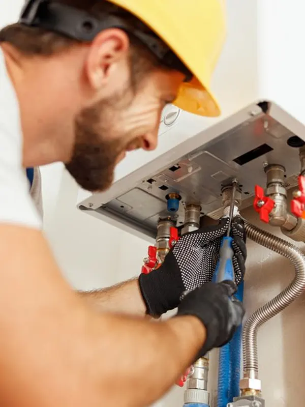 A Jersey boiler engineer in a hard hat and gloves repairing a gas boiler, ensuring safe and efficient heating system maintenance.