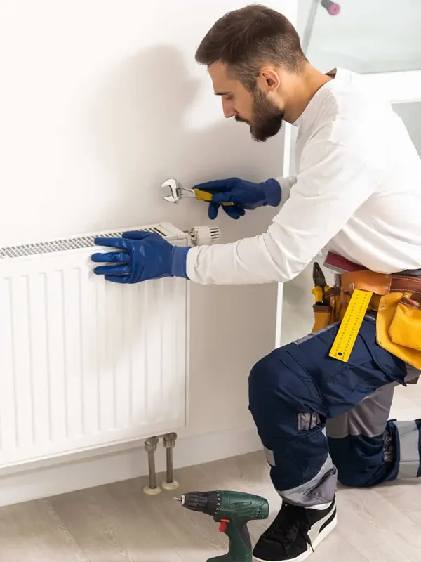A heating engineer installing a central heating radiator, in Jersey ensuring efficient home heating system setup