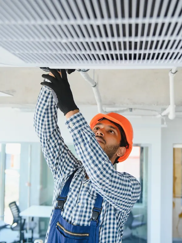 A heating engineer performing maintenance on a ceiling-mounted heating in Jersey.