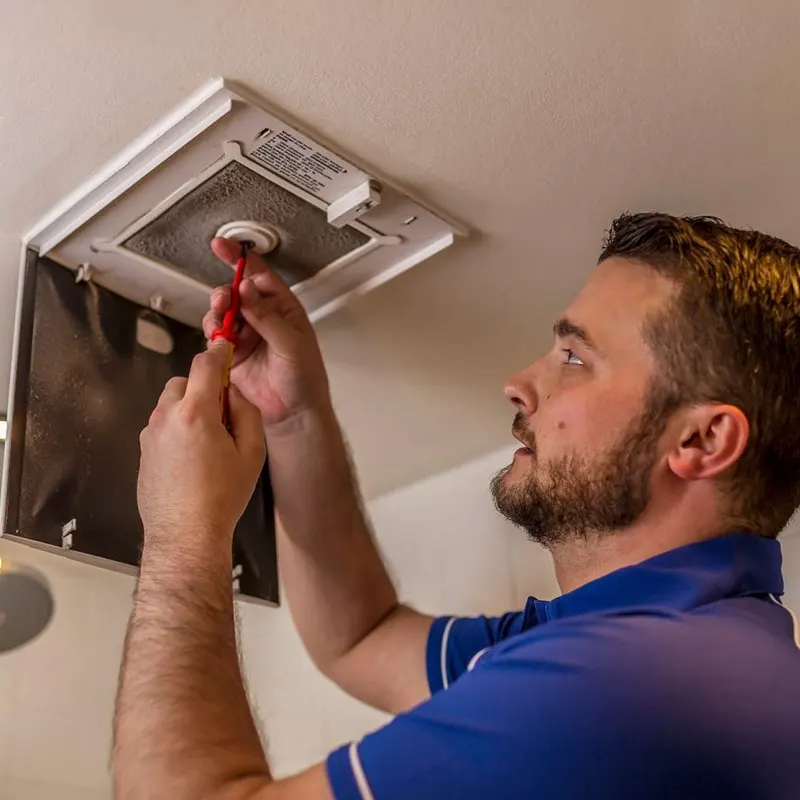 An extractor fan tradesman doing a repair work in a Jersey home.